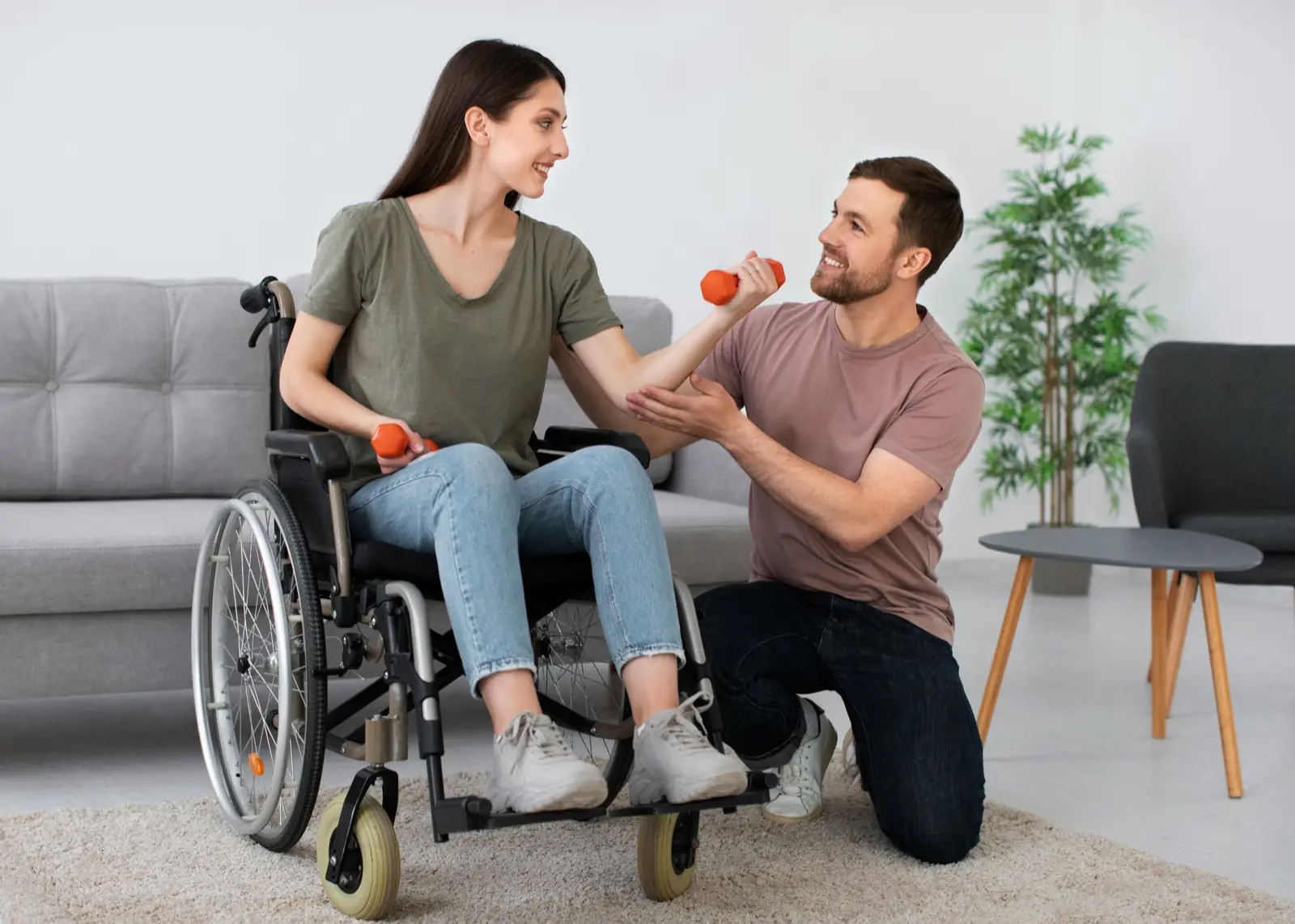 A support professional guiding a wheelchair user through a light arm exercise